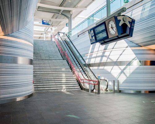 Commuters walking up a wide stone staircase inside a clean train station